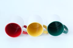 Three mugs red, yellow, green lie on a white background. stock photography Three mugs red, yellow, green lie on a white background. stock photography