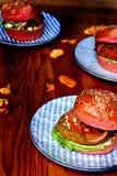 Three vegetarian burgers in pink buns on blue plates stock image Three vegetarian burgers in pink buns on blue plates stock image