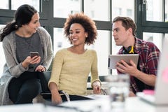Three young employees using modern devices during break Stock Photos Three young employees using modern devices during break Stock Photos