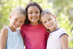 Three young girl friends standing outdoors smiling stock image Three young girl friends standing outdoors smiling stock image