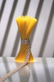 Tied spaghetti pack, on reflective board in stripped grey background stock image Tied spaghetti pack, on reflective board in stripped grey background stock image