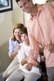Tiener en ouders die thuis opgewekt kijken stock fotografie Tiener en ouders die thuis opgewekt kijken stock fotografie