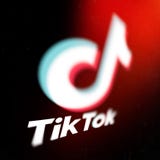 Tiktok logo on smartphone screen on black background. TikTok is a popular video-sharing social networking service owned