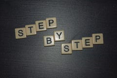 Tile letters step by step progression on a black background. Concept for business, personal or other goal-setting initiatives. Mot stock photography Tile letters step by step progression on a black background. Concept for business, personal or other goal-setting initiatives. Mot stock photography