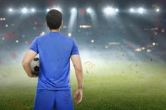 Tillbaka sikt av det asiatiska fotbollsspelareanseendet med bollen royaltyfri bild Tillbaka sikt av det asiatiska fotbollsspelareanseendet med bollen royaltyfri bild