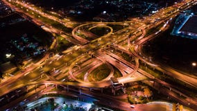 Time-lapse of car traffic transport on multiple lane highway or winding road expressway in Asia city at night, drone aerial view