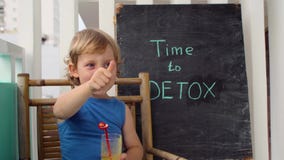 TIME TO DETOX chalk inscription. The boy is drinking fresh, healthy, detox drink made from fruits. Fruit shake, fresh juice, milks