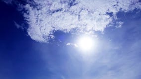 TimeLapse of beautiful sunny blue sky with bright sun light shining through white clouds