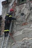 TIMISOARA, ΡΟΥΜΑΝΙΑ 03 13 2011 ένας πυροσβέστης στον πλήρη προστατευτικό εξοπλισμό που αναρριχείται σε μια σκάλα αφαιρεί τα κομμά στοκ φωτογραφίες TIMISOARA, ΡΟΥΜΑΝΙΑ 03 13 2011 ένας πυροσβέστης στον πλήρη προστατευτικό εξοπλισμό που αναρριχείται σε μια σκάλα αφαιρεί τα κομμά στοκ φωτογραφίες