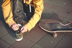 Tinejder przed jeździć na deskorolce wiąże up shoelaces na sneakers zdjęcie royalty free Tinejder przed jeździć na deskorolce wiąże up shoelaces na sneakers zdjęcie royalty free