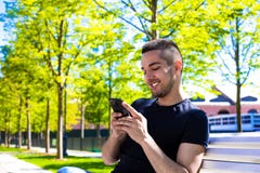Tipo allegro dei pantaloni a vita bassa online che chiacchiera tramite cellulare, sedentesi nel parco della città nel giorno di e immagini stock libere da diritti Tipo allegro dei pantaloni a vita bassa online che chiacchiera tramite cellulare, sedentesi nel parco della città nel giorno di e immagini stock libere da diritti