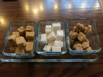 Tipo differente di zucchero di cubo bianco e crudo su fondo scuro fotografia stock Tipo differente di zucchero di cubo bianco e crudo su fondo scuro fotografia stock