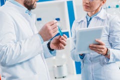 tir cultivé des scientifiques dans des manteaux blancs avec le tube avec du réactif et le comprimé images libres de droits tir cultivé des scientifiques dans des manteaux blancs avec le tube avec du réactif et le comprimé images libres de droits