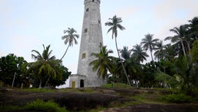 Tirado de la tierra del faro hermoso que se coloca en una colina en una isla tropical almacen de metraje de vídeo Tirado de la tierra del faro hermoso que se coloca en una colina en una isla tropical almacen de metraje de vídeo