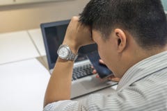 Tired Asian businessman with laptop computer at office stock photo Tired Asian businessman with laptop computer at office stock photo