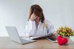 Tired forçou o doutor asiático novo com mãos na cara sofre da depressão severa no local de trabalho imagem de stock Tired forçou o doutor asiático novo com mãos na cara sofre da depressão severa no local de trabalho imagem de stock