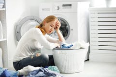 Tired unhappy woman housewife fold clothes into the washing mac Royalty Free Stock Photography Tired unhappy woman housewife fold clothes into the washing mac Royalty Free Stock Photography