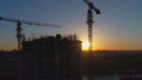 Tiro aéreo del emplazamiento de la obra con las grúas y los trabajadores en la puesta del sol metrajes Tiro aéreo del emplazamiento de la obra con las grúas y los trabajadores en la puesta del sol metrajes