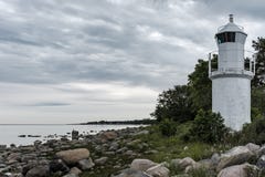 Tiro de la costa rocosa hermosa del mar con una torre blanca del faro en el lado imagen de archivo libre de regalías Tiro de la costa rocosa hermosa del mar con una torre blanca del faro en el lado imagen de archivo libre de regalías