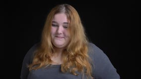 Tiro del primo piano di giovane femmina caucasica di peso eccessivo che è timida e che esamina macchina fotografica che sorride c stock footage Tiro del primo piano di giovane femmina caucasica di peso eccessivo che è timida e che esamina macchina fotografica che sorride c stock footage