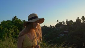 Tiro slowmotion super de uma jovem mulher em um vestido amarelo que anda durante o por do sol na caminhada ou no pintor do cume d vídeos de arquivo Tiro slowmotion super de uma jovem mulher em um vestido amarelo que anda durante o por do sol na caminhada ou no pintor do cume d vídeos de arquivo