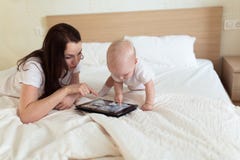 Toddler with her mother playing on the bed in the tablet, Royalty Free Stock Photography Toddler with her mother playing on the bed in the tablet, Royalty Free Stock Photography