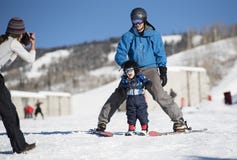 Toddler Screams with Delight as he Learns to Ski with Dad While Mom takes a Photo stock images Toddler Screams with Delight as he Learns to Ski with Dad While Mom takes a Photo stock images
