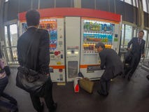 Japanese salary man picking his drink up from drinking vending m royalty free stock photos Japanese salary man picking his drink up from drinking vending m royalty free stock photos