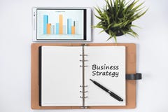 Tom anteckningsbok med ord för AFFÄRSSTRATEGI och digital minnestavla med affärsdiagrammet på den lekmanna- vitlägenheten royaltyfria foton Tom anteckningsbok med ord för AFFÄRSSTRATEGI och digital minnestavla med affärsdiagrammet på den lekmanna- vitlägenheten royaltyfria foton