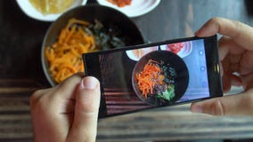 Tomar la foto de la comida del Bibimbap coreano tradicional del plato sirvió junto con pequeños acompañamientos clled banchan en almacen de video Tomar la foto de la comida del Bibimbap coreano tradicional del plato sirvió junto con pequeños acompañamientos clled banchan en almacen de video