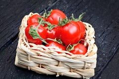 Tomates-cerises fraîches dans un panier sur la table rustique noire photos stock Tomates-cerises fraîches dans un panier sur la table rustique noire photos stock