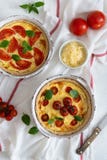 Tomato pies with basil leaves, chicken ans cheese on white tablecloth. Homemade french quiche. Top view stock photo Tomato pies with basil leaves, chicken ans cheese on white tablecloth. Homemade french quiche. Top view stock photo