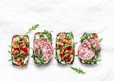 Tomatoes And Italian Salami Sausage Rye Bread Bruschetta On A Light Background, Top View. Copy Space. Delicious Appetizers For Royalty Free Stock Photography Tomatoes And Italian Salami Sausage Rye Bread Bruschetta On A Light Background, Top View. Copy Space. Delicious Appetizers For Royalty Free Stock Photography