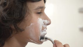 Ton?ringen rakar f?rsta g?ng, den ton?rs- pojken som applicerar raka skum, skincare, kr?m, framsidan, n?rbild lager videofilmer Ton?ringen rakar f?rsta g?ng, den ton?rs- pojken som applicerar raka skum, skincare, kr?m, framsidan, n?rbild lager videofilmer