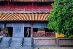 Ton/Vietnam, 17/11/2017: Kvinnaanseende inom ett traditionellt hus med det dekorativa belade med tegel taket i citadellen av tone royaltyfri bild Ton/Vietnam, 17/11/2017: Kvinnaanseende inom ett traditionellt hus med det dekorativa belade med tegel taket i citadellen av tone royaltyfri bild