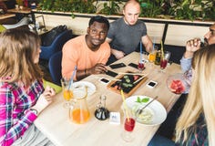 Top besk?dar Ett f?retag av m?ngkulturella f?retagsungdomari ett kaf? som ?ter sushirullar som dricker drinkar som har gyckel royaltyfria bilder Top besk?dar Ett f?retag av m?ngkulturella f?retagsungdomari ett kaf? som ?ter sushirullar som dricker drinkar som har gyckel royaltyfria bilder