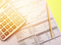 Top view of calculator, pencil and company summary data charts on yellow background Stock Photos Top view of calculator, pencil and company summary data charts on yellow background Stock Photos