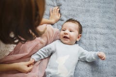 Top view and close-up portrait of cute adorable baby boy wearing blue body in bedroom looking at mother. Newborn child stock photography Top view and close-up portrait of cute adorable baby boy wearing blue body in bedroom looking at mother. Newborn child stock photography