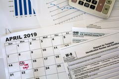 Top view of desk with calculator, tax forms, graphs and calendar sheet with tax date marked royalty free stock image Top view of desk with calculator, tax forms, graphs and calendar sheet with tax date marked royalty free stock image