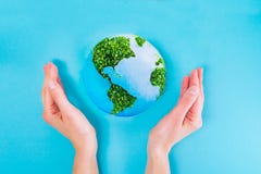 Top view Female Hands holding Earth paper and green sprouts collage model on blue background. Earth in your hands, Saving Earth co royalty free stock photos Top view Female Hands holding Earth paper and green sprouts collage model on blue background. Earth in your hands, Saving Earth co royalty free stock photos