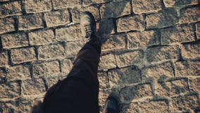 Top view POV of man in shoes walking at historical ancient sidewalk