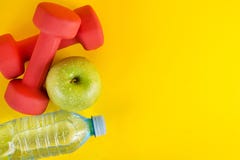 Top view of red dumbbells, green apple and fresh water bottle with dew on yellow background and space Stock Photo Top view of red dumbbells, green apple and fresh water bottle with dew on yellow background and space Stock Photo