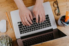 Top View of trendy wooden Office Desk with keyboard, white earphones and office supplies, working mans hands stock images Top View of trendy wooden Office Desk with keyboard, white earphones and office supplies, working mans hands stock images