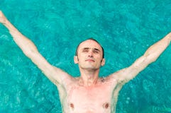 Top view of a young man floating in swimming pool with open arms stock photo Top view of a young man floating in swimming pool with open arms stock photo