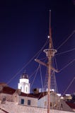 Topmast e cabos de um navio velho da época das descobertas contra uma torre de sino clara na noite fotografia de stock royalty free Topmast e cabos de um navio velho da época das descobertas contra uma torre de sino clara na noite fotografia de stock royalty free