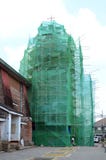 Torre de iglesia cubierta en red y andamio de la construcción bajo renovación imagenes de archivo Torre de iglesia cubierta en red y andamio de la construcción bajo renovación imagenes de archivo