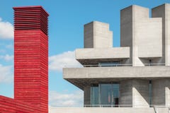 Torre vermelha feita da madeira ao lado de uma construção concreta com torres concretas e do céu azul com nuvens brancas Fotografia de Stock Torre vermelha feita da madeira ao lado de uma construção concreta com torres concretas e do céu azul com nuvens brancas Fotografia de Stock
