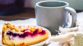 Torta di formaggio del mirtillo sul piatto e su una tazza di caffè immagini stock Torta di formaggio del mirtillo sul piatto e su una tazza di caffè immagini stock