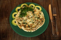 Tortilla con perejil y el aguacate frescos en una placa verde en un fondo rústico de madera foto de archivo Tortilla con perejil y el aguacate frescos en una placa verde en un fondo rústico de madera foto de archivo