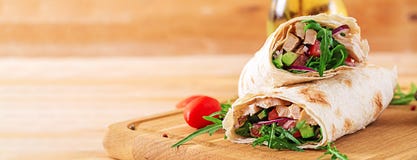 Tortillas wraps with chicken and vegetables on wooden background. Chicken burrito. Banner. Healthy food stock photo Tortillas wraps with chicken and vegetables on wooden background. Chicken burrito. Banner. Healthy food stock photo